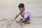 Asian boy playing with sand in a sandcastle shape on the beach.