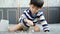 Asian boy sits and puts coins in a glass jar to save money to buy toys