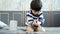 Asian boy sits and puts coins in a glass jar to save money to buy toys