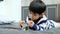 Asian boy sits and puts coins in a glass jar to save money to buy toys