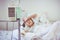 Asian boy sleeping on sickbed with infusion pump intravenous IV