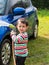 Asian boy washing blue car by green water sprayer