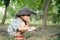 Asian boy wearing a hat in a forest exploration suit Use a magnifying glass to survey the tree area