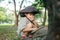 Asian boy wearing a hat in a forest exploration suit Use a magnifying glass to survey the tree area