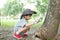 Asian boy wearing a hat in a forest exploration suit Use a magnifying glass to survey the tree area