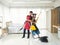 Asian boyfriend and girlfriend playing with cleaning while holding yellow twist mob and vacuum cleaner in the white bedroom at