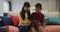 Asian brother and sister smiling and using tablet sitting on sofa at home