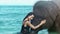 Asian brunette woman interacting with big thai elephant in sea waves on tropical island. Human and wild animal. Concept