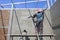 Asian builder worker on wooden platform using long trowel to polishing concrete wall in house construction site