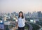 Asian business woman looking at Bangkok city at sunset on rooftop