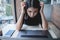 Asian business woman sitting in cafe and touching head in hands. Hand presses on the head