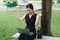 Asian business woman smiling and raising up two hands to celebrate for business successful. she sitting in the garden with laptop.