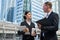 Asian business woman wear suit holding document file and plastic mug on hand talk about business future with Caucasian businessman