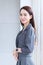 Asian business woman who has long hair wears grey dress stand and smiles happily at office