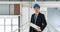 Asian businessman in black suit wearing a blue construction hat,  holding construction drawing. Inspector inspect the orderliness