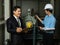 Asian businessman boss wearing black suit standing and discussing with young engineer in elevator machine port. Concept for