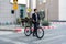 Asian businessman pushes a bicycle across a crosswalk on a city street during a morning commute