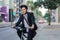 Asian businessman in a suit is riding a bicycle on the city streets for his morning commute to work. Eco Transportation Concept
