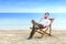 Asian businessman talking on mobile phone while lean back in the beach chair on beach