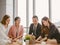 Asian businessmen and businesswoman discussing work sitting at conference table in office.