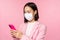 Asian businesswoman in medical face mask using mobile phone. Japenese saleswoman, corporate lady in suit, holding