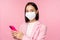 Asian businesswoman in medical face mask using mobile phone. Japenese saleswoman, corporate lady in suit, holding