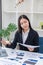 Asian businesswoman sitting at a desk young woman working data analysis charts financial documents with laptop in the office