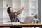 Asian businesswoman stretches her arms to relax her tired muscles from working at her desk all day at the office.