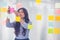 Asian businesswoman using sticky notes on wall