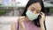 Asian businesswoman wearing protective face mask covering facing camera, urban setting, city life, Covid-19 pandemic