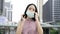 Asian businesswoman wearing protective face mask covering facing camera, urban setting, city life, Covid-19 pandemic