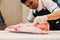 Asian butcher is cutting premium rare slices of Wagyu A5 beef with high-marbled texture on kitchen counter. Served for Yakiniku.