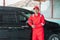 Asian car washer wearing red uniform smiling leaning on the car after finishing car wash