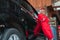 Asian car washer wearing red uniform is standing leaning against the car