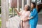 Asian careful caregiver or nurse hold patient hand and encourage patient, walking in garden. Concept of happy retirement with care