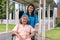 Asian careful caregiver or nurse taking care of the patient in a wheelchair. Concept of happy retirement with care from a