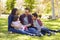 Asian Caucasian mixed race family sitting on grass in a park