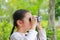 Asian child girl with binoculars in nature fields. Explore and adventure concept