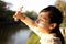 Asian child girl covering face by hand to protect,prevent face skin from bright sun in outdoor summer,female people hand covered