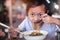 Asian child girl eating noodles with chopstick in restaurant