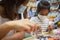 Asian child girl and her mother wearing protection mask making fusible beads thermo mosaic in pegboard that is a toy to develops