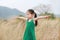 Asian Child girl with outstretched arms in the dried grass field. Rear view