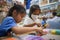 Asian child girl and sister wearing protection mask making fusible beads thermo mosaic in pegboard that is a toy to develops the