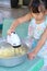 Asian child girl is using an electric beater to beat the dough to make pastries.