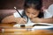 Asian child girl writing and doing her homework at home.