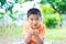 Asian child holding young seedling plant in hands, in garden, on