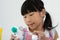 Asian child paints the colors of white plaster doll toys on the table