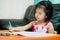 Asian child is sluggish having sleepiness while doing homework. Girl close half eyes. Cute kid aged 4-5 years old