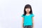 Asian child stands upright looking at the camera. A white wall as a background. Copy space. Kids wear green clothes.