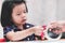 Asian child is using pink scissors to carefully cut the double-sided tape. A 4-5 year old girl is learning to use tools carefully